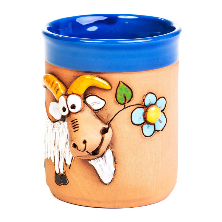 Mėlynas keraminis puodelis su balta ožka, valgančia mėlyną gėlę